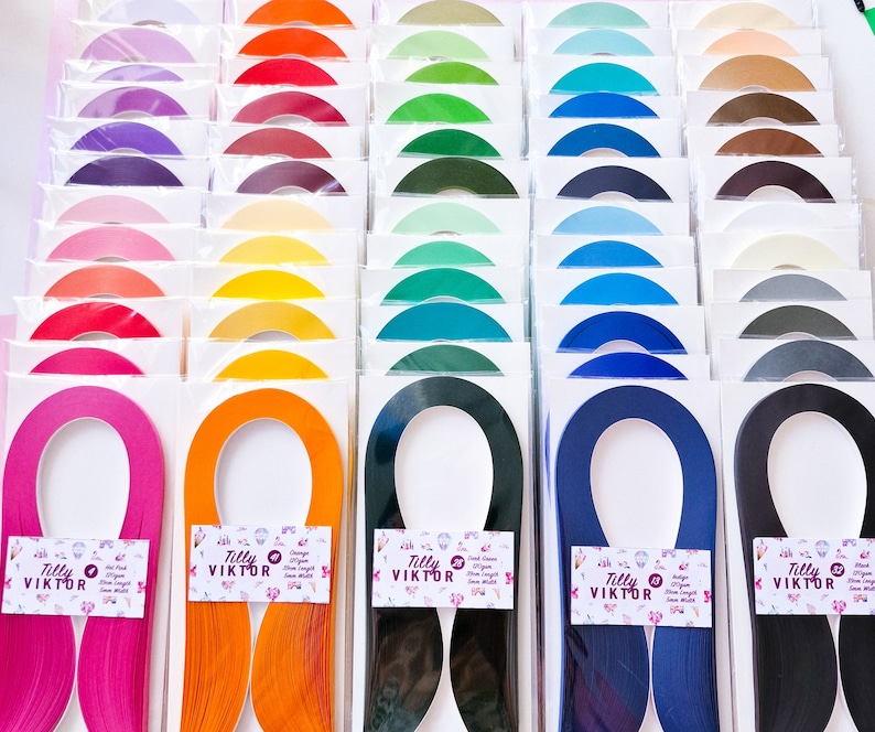 Puede incluir: Surtido de 20 paquetes de tiras de papel para quilling de 5 mm de ancho, de doble cara. Cada paquete presenta un color diferente, incluyendo rosa, naranja, negro y azul. Las tiras de papel est&aacute;n etiquetadas con "Tilly Viktor" y son ideales para proyectos de manualidades de papel.