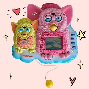 以下が含まれることがあります： ピンクと黄色のタイガーエレクトロニクス製ヴィンテージFurbyおもちゃ。ピンクのFurbyは空のシーンを表示する画面があります。黄色のFurbyは胸に「Furby」の文字が入っています。どちらも青い目を持ち、青い雲のベースに乗っています。