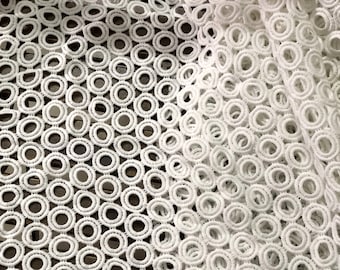 May include: White crochet fabric with a repeating pattern of concentric circles.