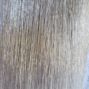 May include: Close-up of a silver beaded fabric. The beads are small, cylindrical, and densely packed, creating a shimmering, textured surface. The beads are arranged in vertical rows, giving the fabric a draped appearance. The background is a soft, off-white color.