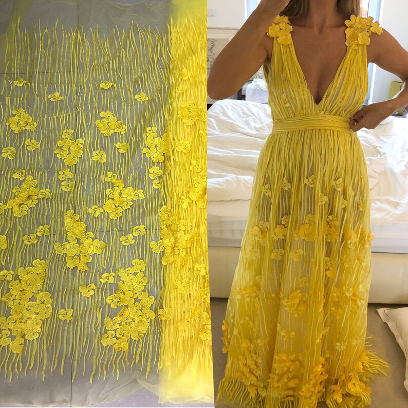 May include: Yellow floral lace fabric with a delicate pattern of small flowers. The fabric is sheer and has a soft, flowing texture.