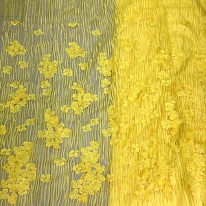 May include: Yellow floral lace fabric with a textured design. The lace has a delicate, floral pattern and is perfect for adding a touch of elegance to any project.
