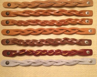 May include: Seven braided leather bracelets with silver clasps. The bracelets are in various colors, including brown, tan, burgundy, and gray.