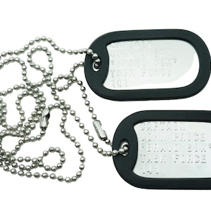 May include: Two silver dog tags with black rubber coating on a silver ball chain. The tags have engraved text.