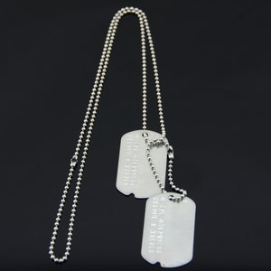 以下が含まれることがあります： 銀色のチェーンネックレスに、銀色のドッグタグが2つ付いています。ドッグタグは空白です。