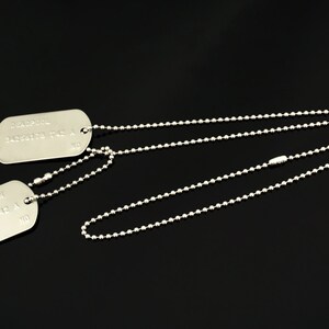 Puede incluir: Dos chapas de identificaci&oacute;n militares de plata en un collar de cadena de bolas de plata. La chapa superior dice "CHARLIE  1450172  1st  A  NO". La chapa inferior dice "WADE WILSON  1450172  1st  A  NO".