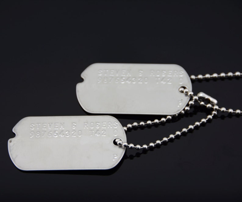 以下が含まれることがあります： 銀色の犬用タグ2つと銀色のチェーン。上のタグには「STEVEN S. ROBERS 987654320 142 C」と書いてあります。下のタグには「STEVEN S. ROBERS 987654320 142 C」と書いてあります。