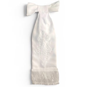 Può includere: Una stola da clero in raso bianco con un fiocco in alto e frange in basso. La stola presenta un simbolo IHS ricamato al centro. Il design è semplice ed elegante, adatto alle cerimonie religiose.