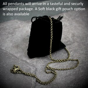 May include: A black velvet gift pouch with a drawstring closure and a bronze-colored chain necklace. The necklace is laid out on a gray stone surface. Text on the image reads: "All pendants will arrive in a tasteful and securly wrapped package. A Soft black gift pouch option is also available."