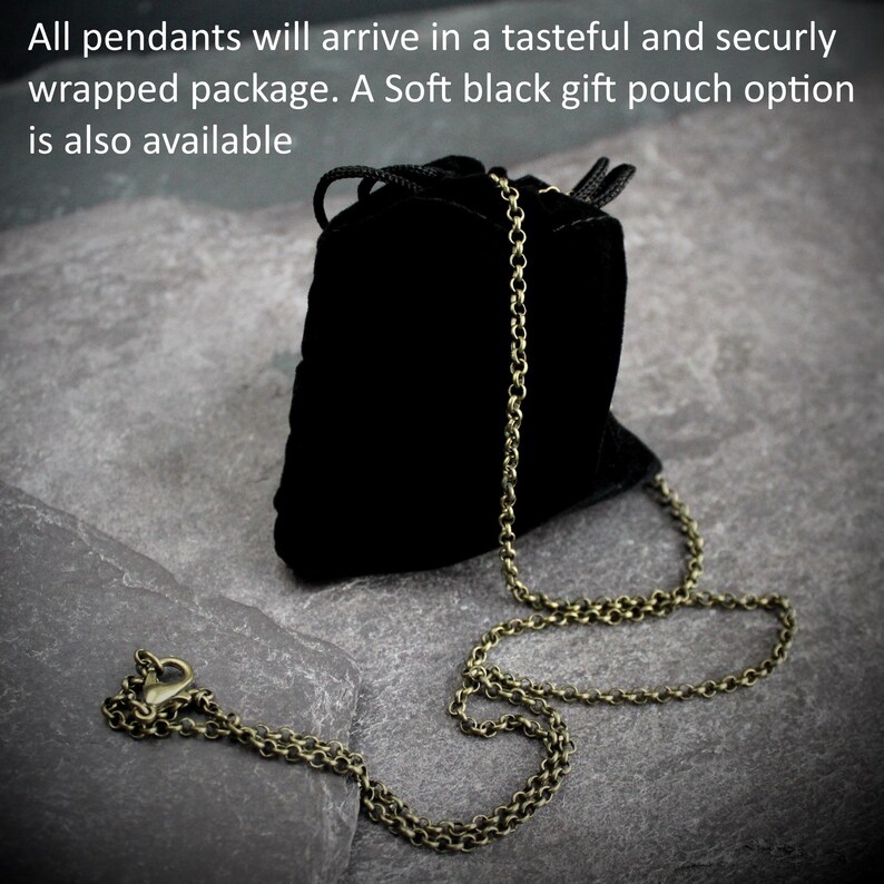 May include: A black velvet gift pouch with a drawstring closure and a bronze-colored chain necklace. The necklace is laid out on a gray stone surface. Text on the image reads: "All pendants will arrive in a tasteful and securly wrapped package. A Soft black gift pouch option is also available."