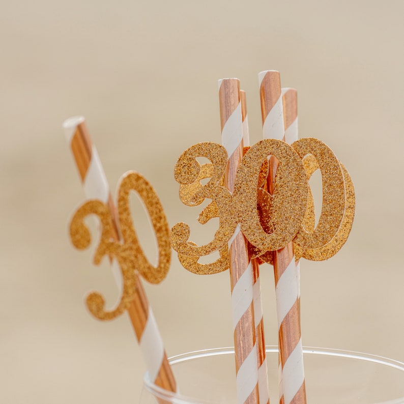 May include: Gold glitter number 30 party decorations on striped paper straws.