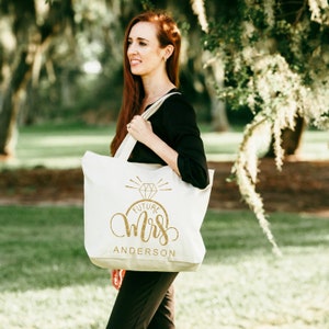 May include: A white canvas tote bag with a gold glitter design that says "Future Mrs. Anderson" with a diamond ring graphic above the text.