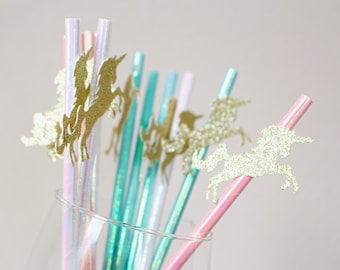 May include: A set of colorful straws with glitter unicorn toppers. The straws are iridescent and come in pink, blue, and green. The unicorn toppers are gold glitter.