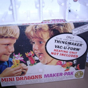 May include: A box for a Mattel Mini Dragons Maker-Pak toy set. The box features a photo of two children making dragons with the toy. The box says "Only to be used with Mattel Thingmaker or Vac-U-Form. Heating Unit Not Included."