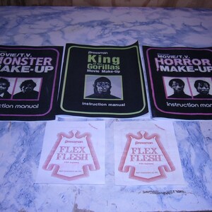 May include: Four instruction manuals for movie and television monster and horror make-up effects. The manuals are black with pink and white text. The manuals feature images of people with make-up effects. Two white sheets of paper with red text that reads "Pressman Flex Flesh" are also shown.