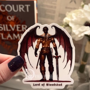 May include: A sticker featuring a muscular figure with large, dark wings and a sword. The figure is depicted from the back, with intricate details on the wings and a tattoo. The text "Lord of Bloodshed" is at the bottom.