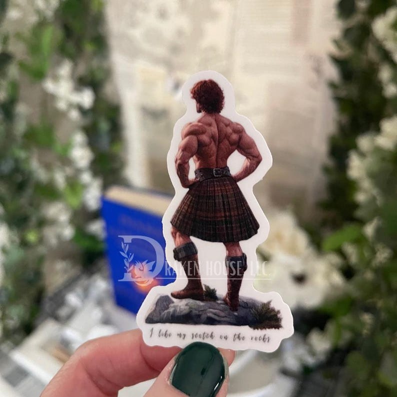 K&ouml;nnte beinhalten: Ein Aufkleber mit einem muskul&ouml;sen Mann, der einen Kilt tr&auml;gt und auf einem Felsen steht, mit dem Text "I take my scotch on the rocks".
