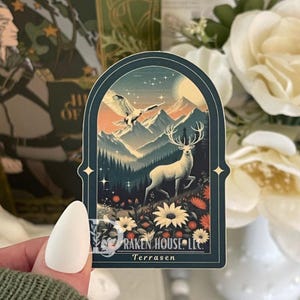 Könnte beinhalten: Ein Aufkleber mit einem bogenförmigen Design, das eine Berglandschaft mit einem Hirsch, einem Adler und Blumen darstellt. Der Aufkleber hat einen dunkelblauen Rand mit dem Text "RAKEN HOUSE LLC" und "Terrasen". Der Hintergrund zeigt einen Sonnenuntergang und einen Vollmond.
