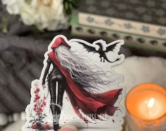May include: A sticker featuring a woman with long white hair wearing a red hooded cloak and black leather pants. She is walking away from the viewer with a black dragon flying behind her. The sticker has a white background and is surrounded by pink flowers.