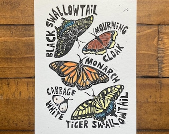 May include: A print featuring six butterfly illustrations with their names: Black Swallowtail, Mourning Cloak, Monarch, Cabbage White, and Tiger Swallowtail. The print is on a white background with black text and butterfly outlines. The text "Butterflies of New York" is at the bottom.