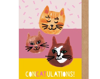 May include: A greeting card with a yellow, pink, and white background featuring three cartoon cat faces. The card says "CONCATULATIONS!" in pink letters.