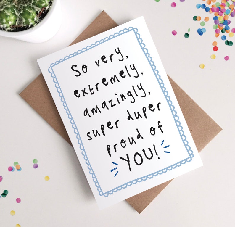 May include: A white card with a blue border and the text "So very, extremely, amazingly, super duper proud of YOU!" written in black.