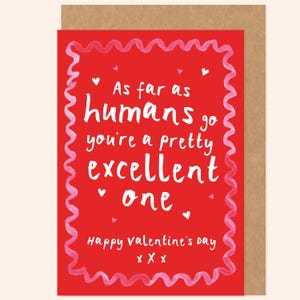Peut inclure: Une carte rouge de la Saint-Valentin avec du texte blanc. La carte dit "As far as humans go you're a pretty excellent one." Elle a une bordure rose ondulée et des accents de cœur. Le bas indique "Happy Valentine's Day" avec trois baisers.