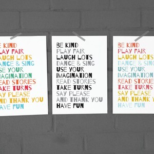 May include: Three white posters with black text on a grey brick wall. The text on each poster reads: "Be Kind, Play Fair, Laugh Lots, Dance & Sing, Use Your Imagination, Read Stories, Take Turns, Say Please, And Thank You, Have Fun."