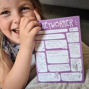 May include: A purple card with the title "Keyworker" and a child's handwritten message about their keyworker. The message includes the keyworker's name, and details about how the keyworker makes the child laugh and helps them learn. The card is decorated with drawings of a smiling face, an apple, and a star.