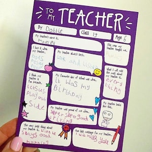 May include: A purple handmade card with the words "TO MY TEACHER" at the top. The card includes handwritten text and drawings, with sections for the teacher's name, age, and favorite things. The card is held by a person.