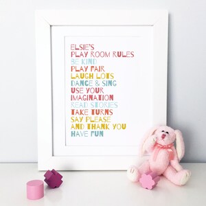 May include: A white framed print with colourful text that reads "Elsie's Play Room Rules" and includes rules like "Be Kind", "Play Fair", "Laugh Lots", "Dance & Sing", "Use Your Imagination", "Read Stories", "Take Turns", "Say Please", "And Thank You", and "Have Fun".