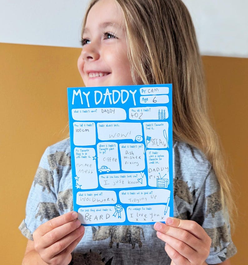 Op de afbeelding: Een felblauwe rechthoekige kaart met de titel My Daddy, witte gedrukte tekst en handgeschreven antwoorden in blauwe inkt. De kaart bevat diverse vragen over een vaderfiguur, waaronder leeftijd, lengte, lievelingseten, beroep en een persoonlijke boodschap.