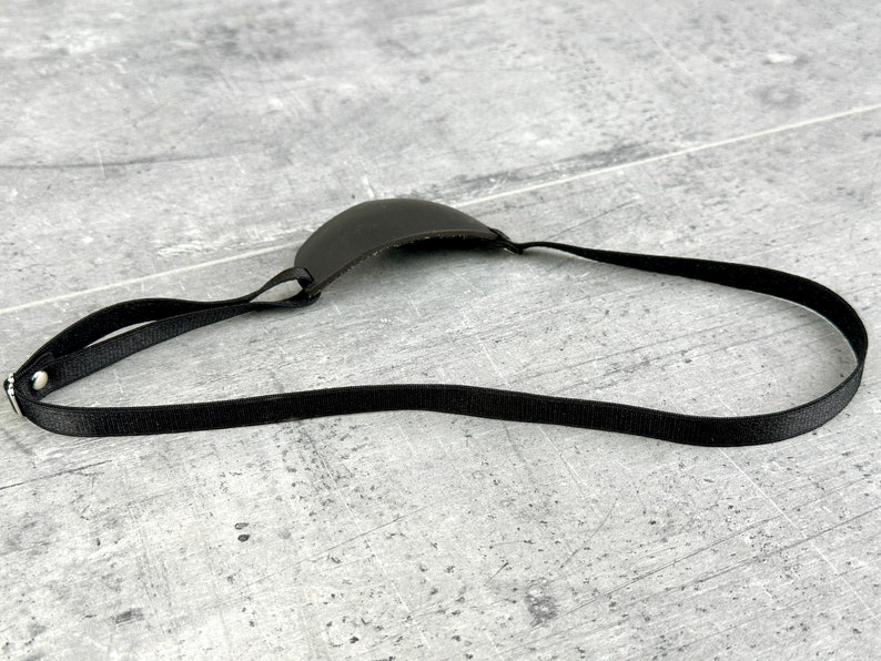 May include: A black leather eye patch with an adjustable strap. The patch is designed to cover one eye.
