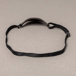 May include: A black headband with a gray fabric covering the top of the head.