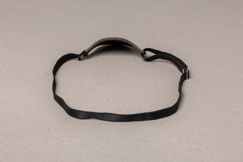 May include: A black headband with a gray fabric covering the top of the head.