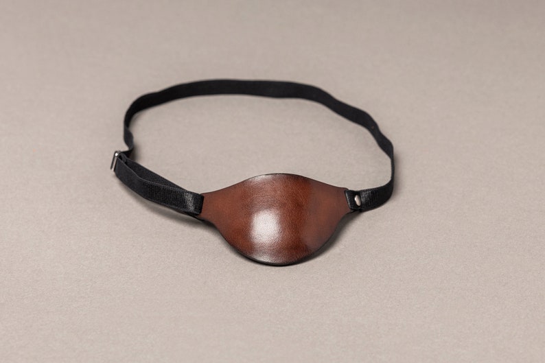 May include: A brown leather eye patch with a black elastic strap.