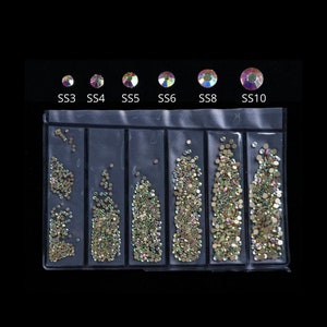 May include: Six clear plastic containers filled with iridescent rhinestones of varying sizes. The containers are labeled SS3, SS4, SS5, SS6, SS8, and SS10.