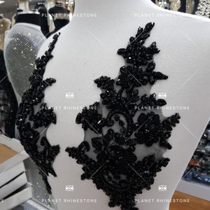 Può includere: Applique floreale nera con perline e retro in rete. L'applique è su un manichino bianco.