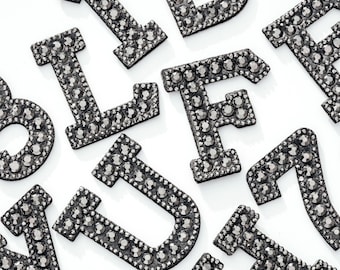 Può includere: Un set di lettere in strass nero, tra cui A, B, F, L, U, Y e Z. Le lettere sono realizzate in strass nero e hanno una finitura lucida.