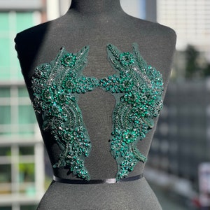 May include: A pair of green beaded appliques with a floral design. The appliques are made of rhinestones and beads and are attached to a sheer fabric.