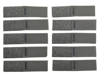 May include: Ten rectangular gray hook and loop fastener strips arranged in two vertical columns. Each strip features a textured fuzzy section on one side and a woven fabric section on the other, joined by a visible line of dark stitching.