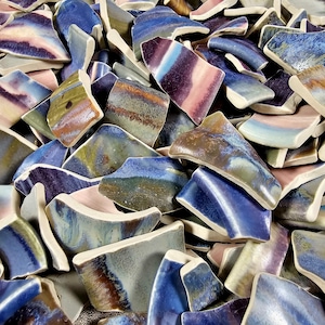 May include: A collection of iridescent ceramic tile shards in shades of blue, green, purple, and pink. The tiles are irregular in shape and size, and have a variety of textures.