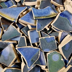 May include: A collection of blue and green ceramic tile pieces, some with a speckled glaze, in various shapes and sizes.