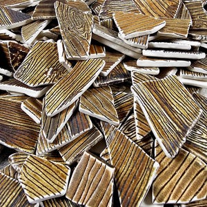 May include: A pile of brown and white ceramic tiles with a wood grain pattern. The tiles are irregular in shape and size.