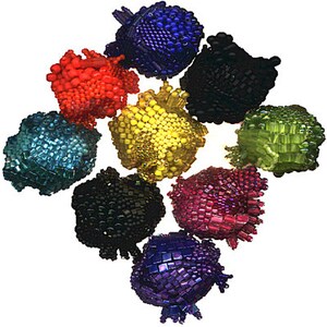 Puede incluir: Una colección de diez adornos de cuentas en varios colores, incluyendo rojo, azul, verde, amarillo, morado y negro. Los adornos son todos redondos y tienen una superficie texturizada.