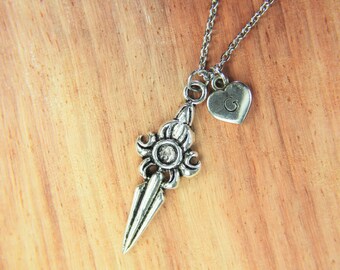 May include: Silver necklace with a key charm and a small heart charm with the letter G engraved on it.