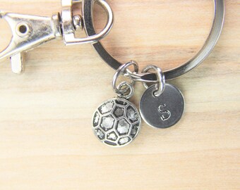 May include: Silver keychain with a soccer ball charm and a round charm with the letter 'S' on it.