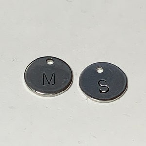 May include: Two silver metal round charms with the letters M and S engraved on them.