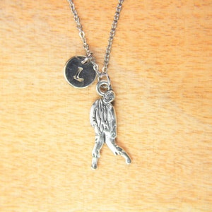 May include: A silver necklace with a silver charm of a zombie and a silver disc charm with the letter 'L' on it.