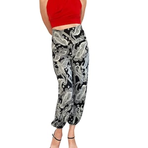 Könnte beinhalten: Schwarz-weiße Hose mit Paisley-Muster und einem roten Halstuch. Die Hose hat eine hohe Taille und eine lockere Passform.